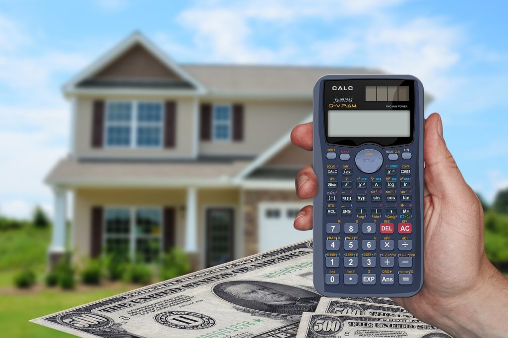 BRRRR vs. Traditional Real Estate Investing visual aid has a hand holding a calculator in front of a house and money.